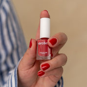 une femme tient un flacon de Vernis Rouge